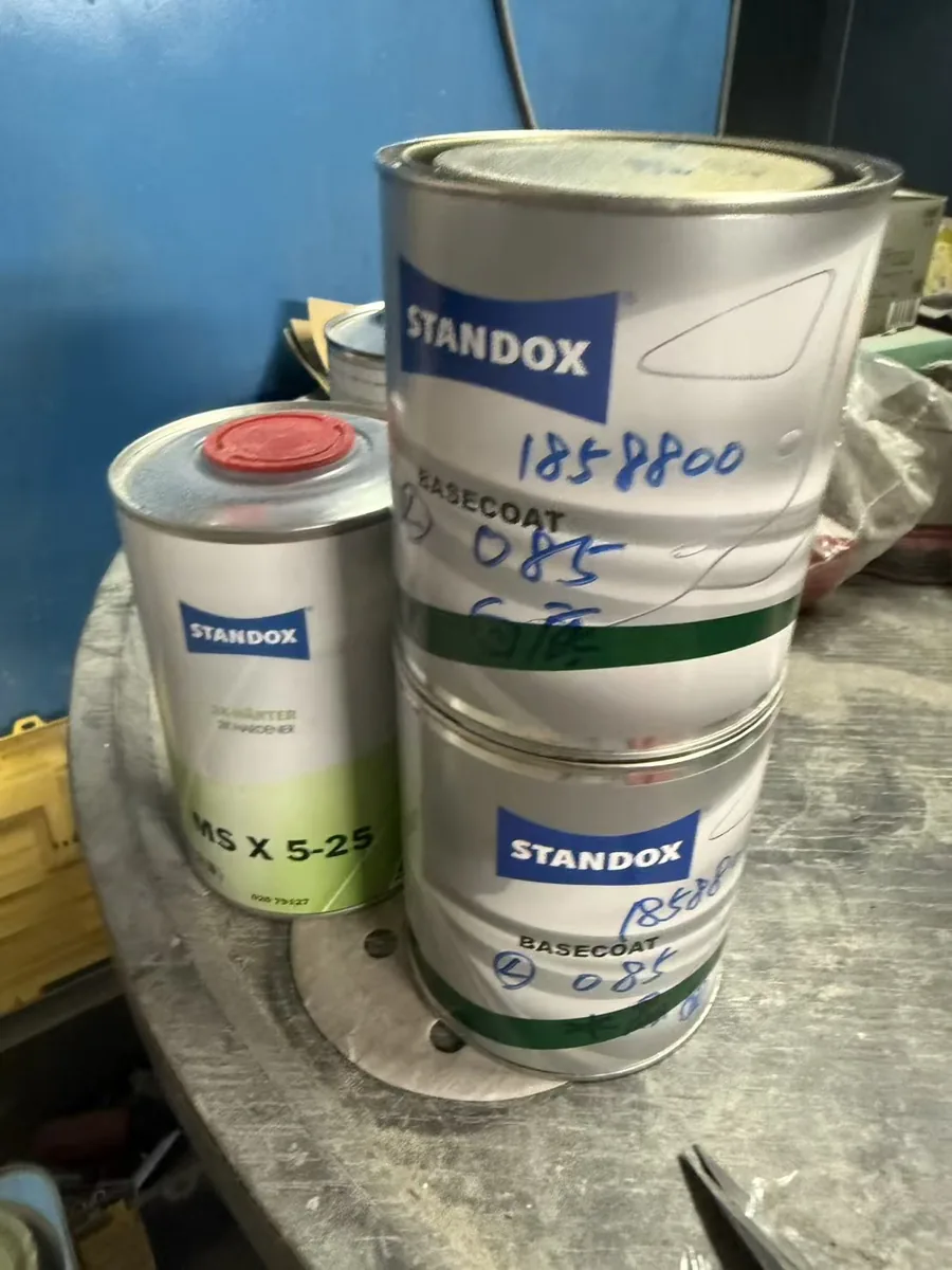 工作台上的 Standox 標籤塗料罐與稀釋劑罐堆放特寫