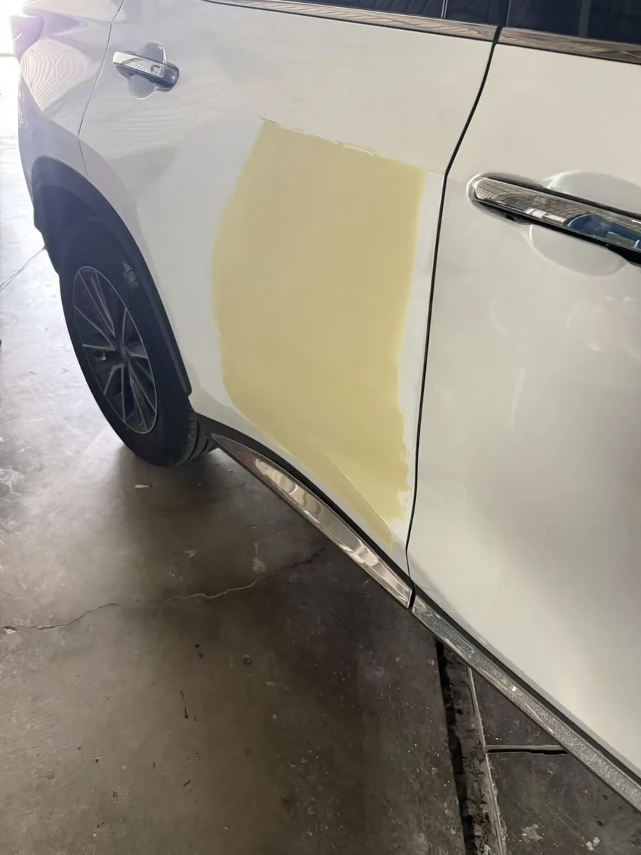 右後車門塗抹黃色補土的修補面，邊緣靠近車門把手並準備打磨