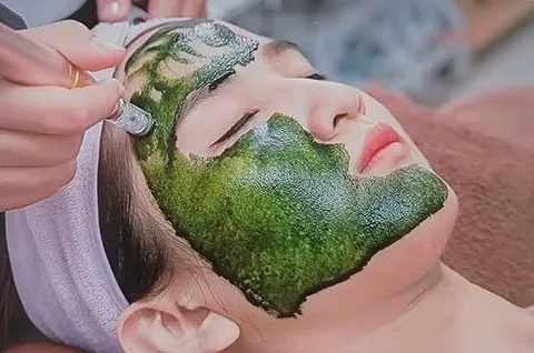 客人臉部覆有深綠色面膜，美容師使用導入儀在臉上操作進行臉部保養—玉湄創藝療程示意 縮圖